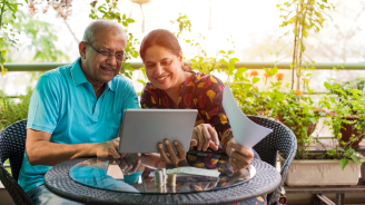 older couple sitting outside with a computer